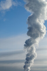 Smoke from a chimney against the sky. Heating season in winter. Vertical frame