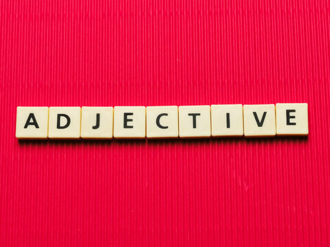 ADJECTIVE word made from square letter tiles on red background.