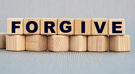 FORGIVE - word on wooden cubes on a beautiful gray background