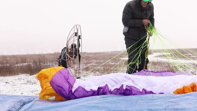 Man paragliders preparing parachute for paramotor paraglider gliding