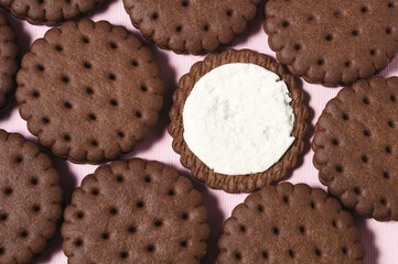 Texture background of rows of chocolate-cream cookies. One cookie with white buttercream.