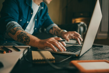 Close-up of male hands with laptop. Man is working remotely at home. Freelancer at work