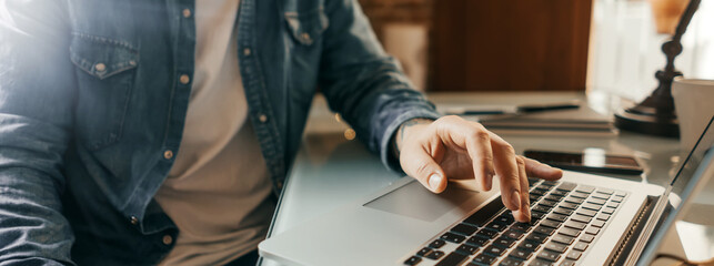 Close-up of male hands with laptop. Man is working remotely at home. Freelancer at work