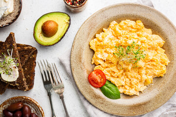 Fresh cooked scrambled eggs in a plate on white background, top view