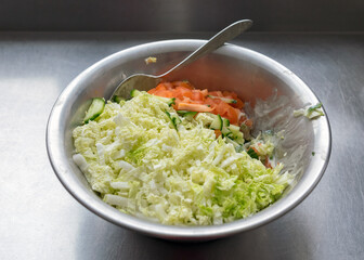 metal bowl with fresh salad of tomatoes, cabbage and cucumbers, eat cooking