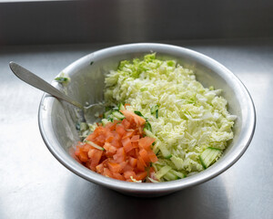 metal bowl with fresh salad of tomatoes, cabbage and cucumbers, eat cooking