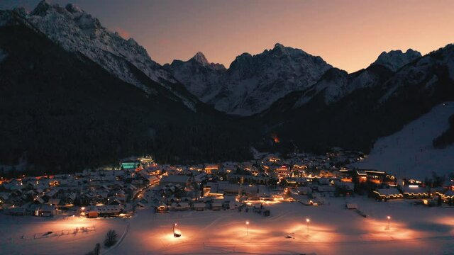 Kranjska gora at winter at night with city lights and snow. Drone shot, aerial view.