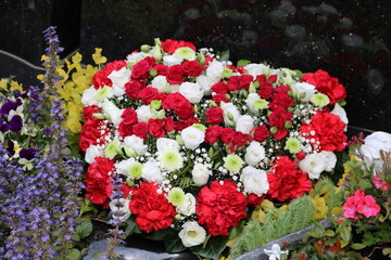 Liebevoller Grabschmuck mit Herz aus Blumen auf dem Friedhof 