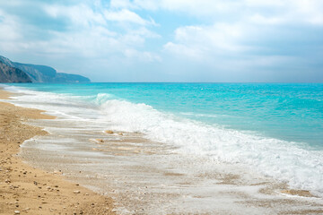 Beautiful sunny sea beach with amazing azure blue water and sky with fluffy clouds.