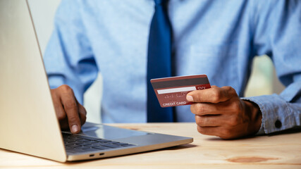 Man holding credit card and using laptop computer. Online shopping concept.
