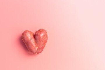 unusually heart shape potato on pink background, food shape