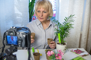 Social media concept. Woman sits at home using a camera and recording an online gardening course