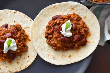 Chilli con carne with Greek yogurt and coriander on Tortillas. Mexican food.