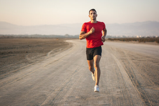 Sporty man jogging on beach and working out in nature