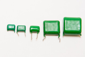 Five green film capacitors. Different size capacitors. On white background