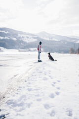 Fototapeta na wymiar Frau und Hund blicken sich in tief verschneiter Landschaft an und absolvieren Hundetraining