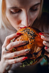 young woman eating a hamburger with hands 