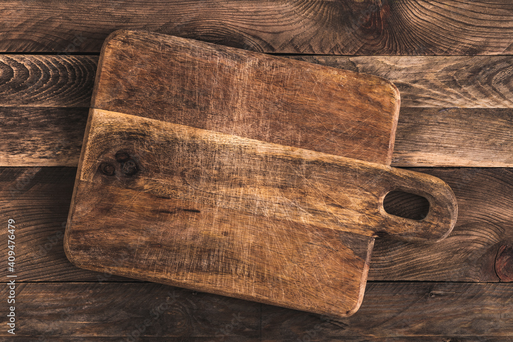 Wall mural Rustic cutting board on wooden table. Overhead view.