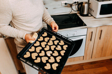 Cookies in shape of heart for the Saint Valentine's Day. Man is baking heart shape cookies for Saint Valentine's Day. Many heart cookies on the baking pan.