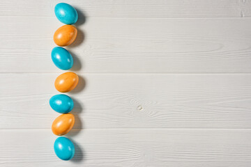 Easter background with painted eggs on a white wooden background with copy space.