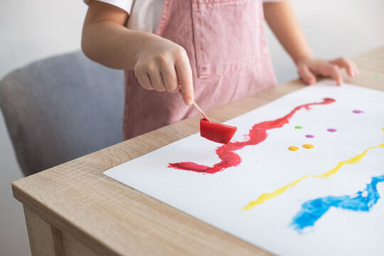 Child painting with colour ice cubes. Creative activities for toddlers. DIY, homemade paints.
