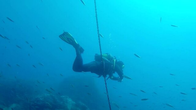buceador baja por la cadena hacia el fondo marino