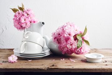 White cups, teapot and  Japanese cherry blossoms.