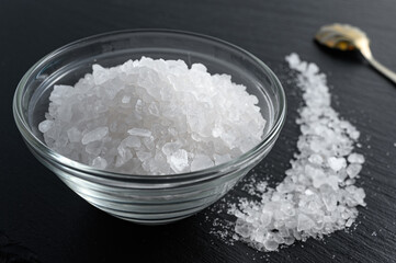 Glass bowl of sea salt on black background
