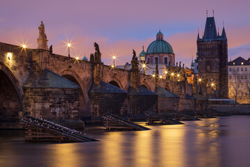 Fototapeta na wymiar View of illuminated historic Charles bridge and Vltava river in Prague, Czech Republic at twilight. Long exposure shot and star effect on street lamps