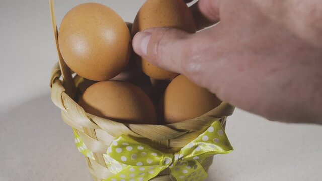 hand putting an egg inside a basket full of eggs, concept of classic American proverb Never put all your eggs in one basket. Idea of financial risks