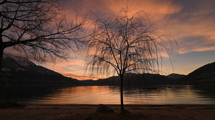 Favoloso tramonto sul lago, con nuvole arancioni e rosse che si riflettono nell'acqua del lago © fotonaturali