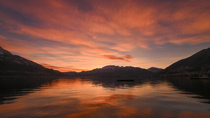 Favoloso tramonto sul lago, con nuvole arancioni e rosse che si riflettono nell'acqua del lago © fotonaturali