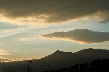 Distant view of Burriac castle in the mountains under amazing clouds in Cabrera de Mar.
