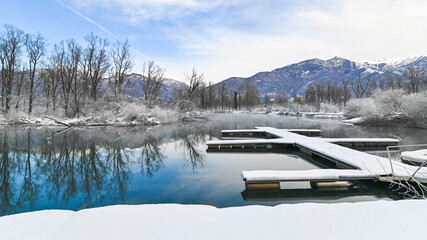 Paesaggio invernale sul lago, circondato dal canneto, in inverno, in una mattinata di cielo azzurro
