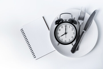 Food clock with notebook. Healthy food concept on white background