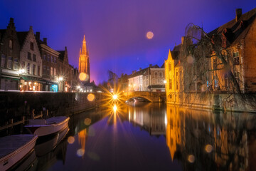 Obraz premium Iconic fairytale view of the canals of Bruges, during the rain. Nepomucenus Bridge and Church of Our Lady Bruges in the background. Belgium