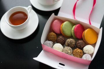 set of truffles and cookies in a box on a table against the background of a teapot
