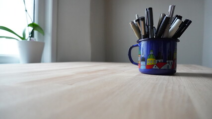 pot of illustrator pens on wooden work desk