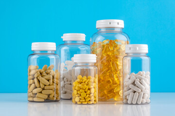 Bottles transparent pills orange capsules blue background. Gel capsules bottle white surface. Nutritional Supplements, Vitamins. Omega 3, multivitamins, Calcium, antibiotics. Health. Immunity