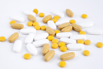 Yellow tablets white capsules gel shell lying on white background close-up. Omega 3, Multivitamins, Calcium, Antibiotics. Health. Immunity. Taking medication, pills. Nutritional supplement. Copy space