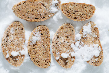Flat lay of frozen grey bread slices in a grinded ice. top view. Resting flat, arranged in two rows.