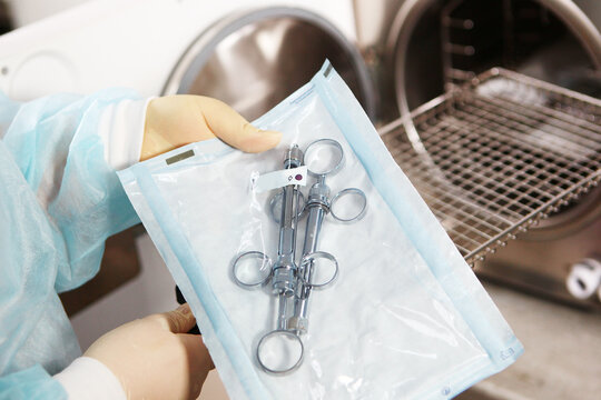 A dental clinic employee puts sterilization instruments in a dry firing cabinet. The concept of sterility and hygiene in the clinic. Unrecognizable person. Only hand.