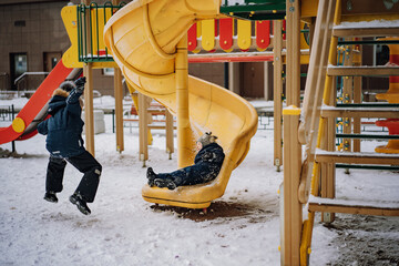 little brothers have fun on playground. sliding down and running. Image with selective focus