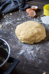 Gnocchi preparation steps: Homemade gluten free mashed potato puree dough on dark table. Flour, measure cup, towel and eggshells in the background. Creating authentic pasta dough for an Italian dish.