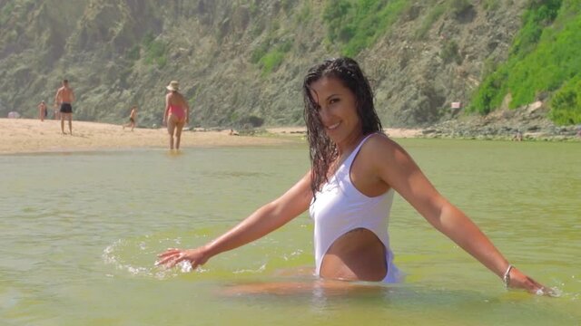 mujer joven y atractiva ba&ntilde;&aacute;ndose en el agua verde en el para&iacute;so tropical en playa de Odeceixe, en Portugal