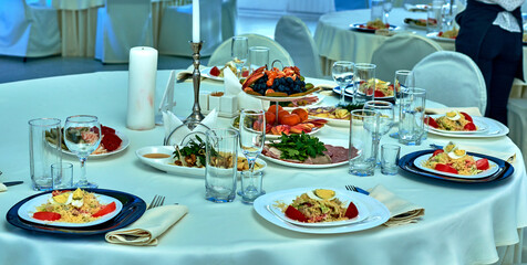 Decor and decoration of the festive table.Banquet table festive at the event in the restaurant. Wine glasses for wine. Plates with snacks. Fruit. A set festive table. The waitress.