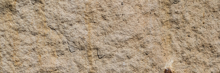 Ancient stone wall. Weathered rough masonry surface. The wall of the old castle. Wide panoramic texture for background and design.