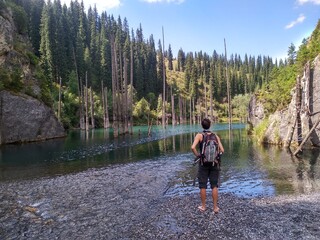 White man at the peaceful Kaindy lake in the Kazakhstan forest