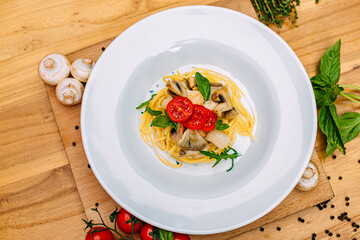 spaghetti with mushrooms and tomatoes in a creamy sauce on a decorated table