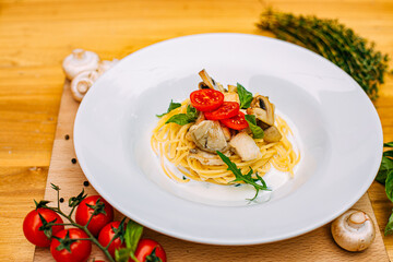 spaghetti with mushrooms and tomatoes in a creamy sauce on a decorated table